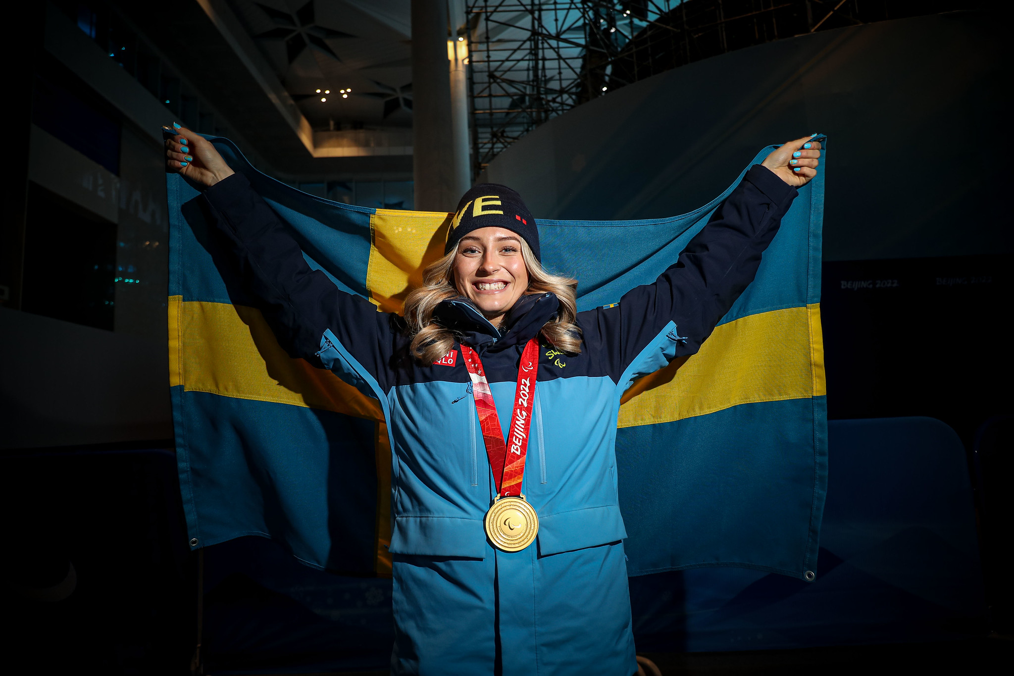 Ebba Årsjö, med guldmedalj runt halsen, håller upp den svenska flaggan bakom sig.